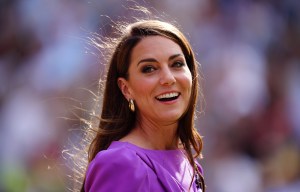 a woman in a purple dress smiles with her hair blowing in the wind