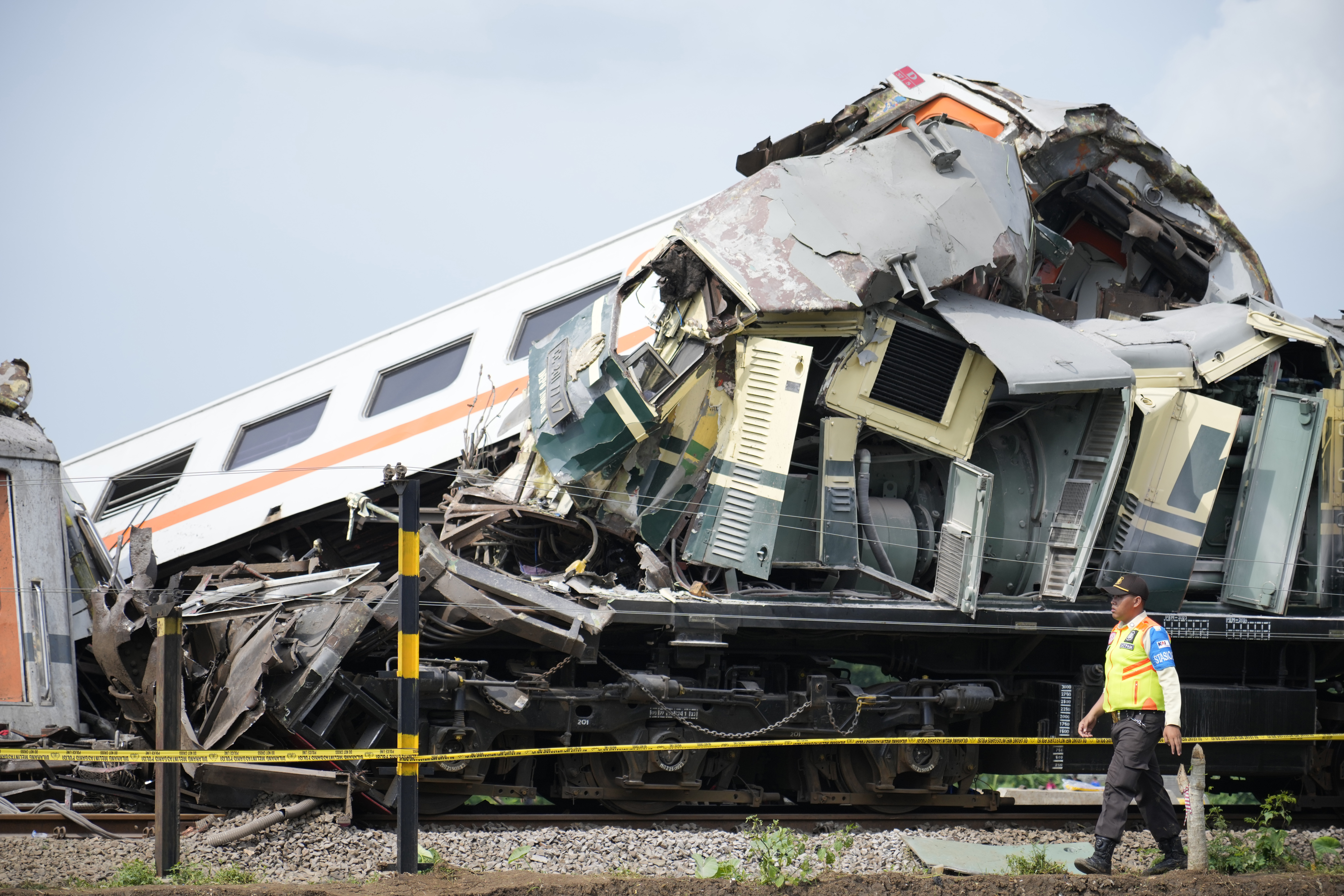 An inspector walks near the wreckage after the collision between two trains in Cicalengka, West Java, Indonesia, Friday, Jan. 5, 2024. The trains collided on Indonesia's main island of Java on Friday, causing several carriages to buckle and overturn, officials said. (AP Photo/Achmad Ibrahim)