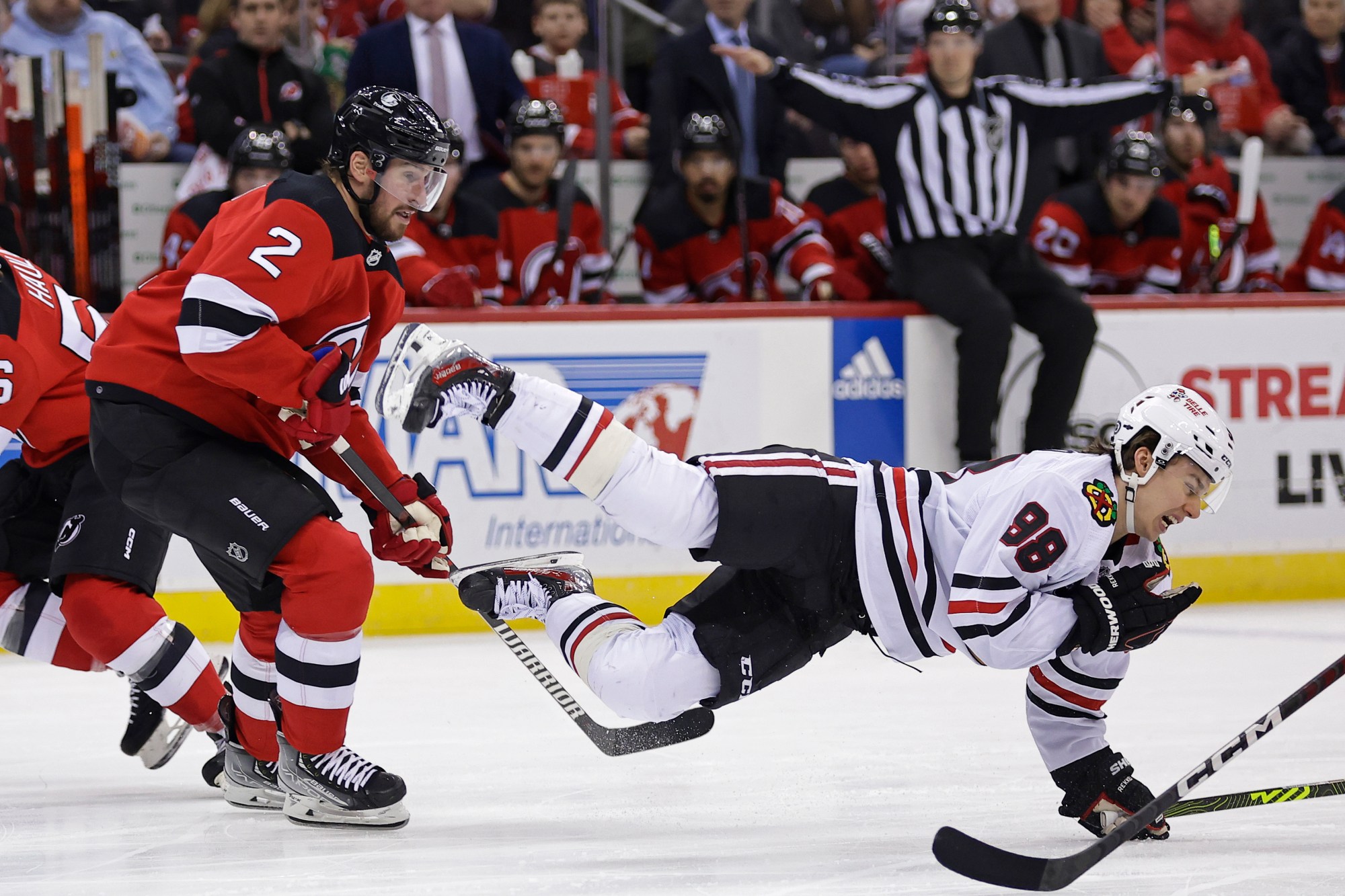 Chicago Blackhawks center Connor Bedard falls to the ice after being checked by New Jersey Devils defenseman Brendan Smith (2) during the first period of an NHL hockey game Friday, Jan. 5, 2024, in Newark, N.J. (AP Photo/Adam Hunger)