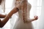 woman having her wedding dress buttoned up